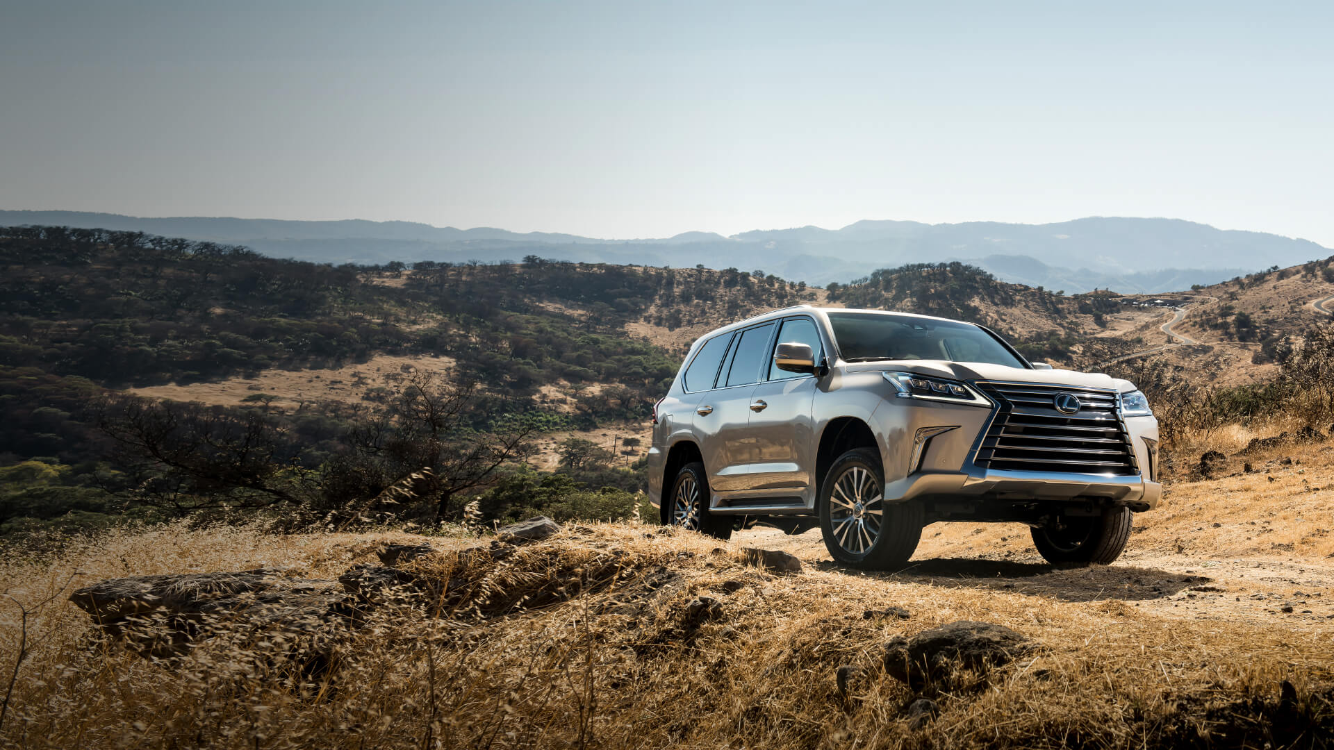 Silver Lexus LX being driven in mountainous terrain.